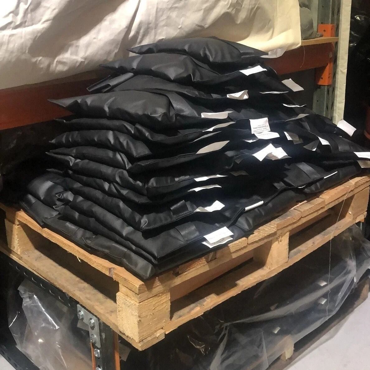 Black shotbags stacked on a wooden pallet in a warehouse
