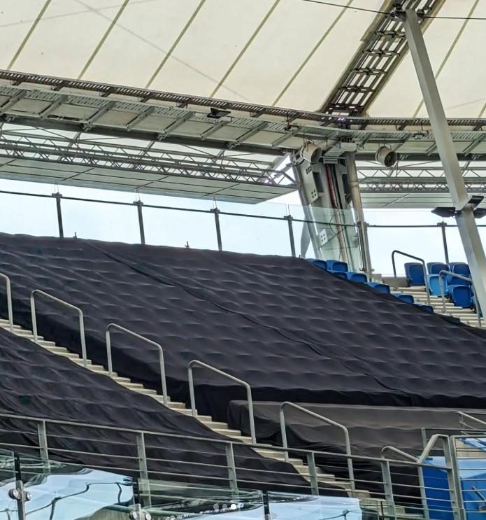 Black covers closing off a bank of stadium seating, fitted around the handrails and down the steps
