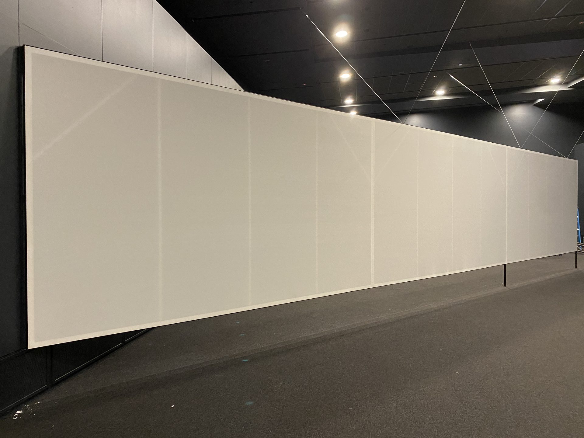 A long white cyclorama wall finished along a dark venue