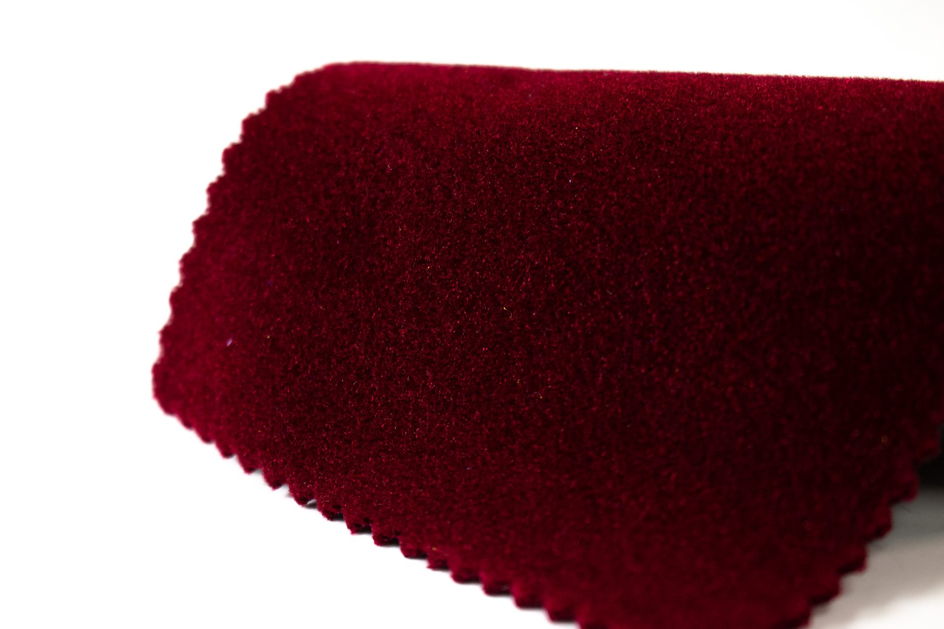 Wine velvet swatch with a pinked edge, photographed in true colour
