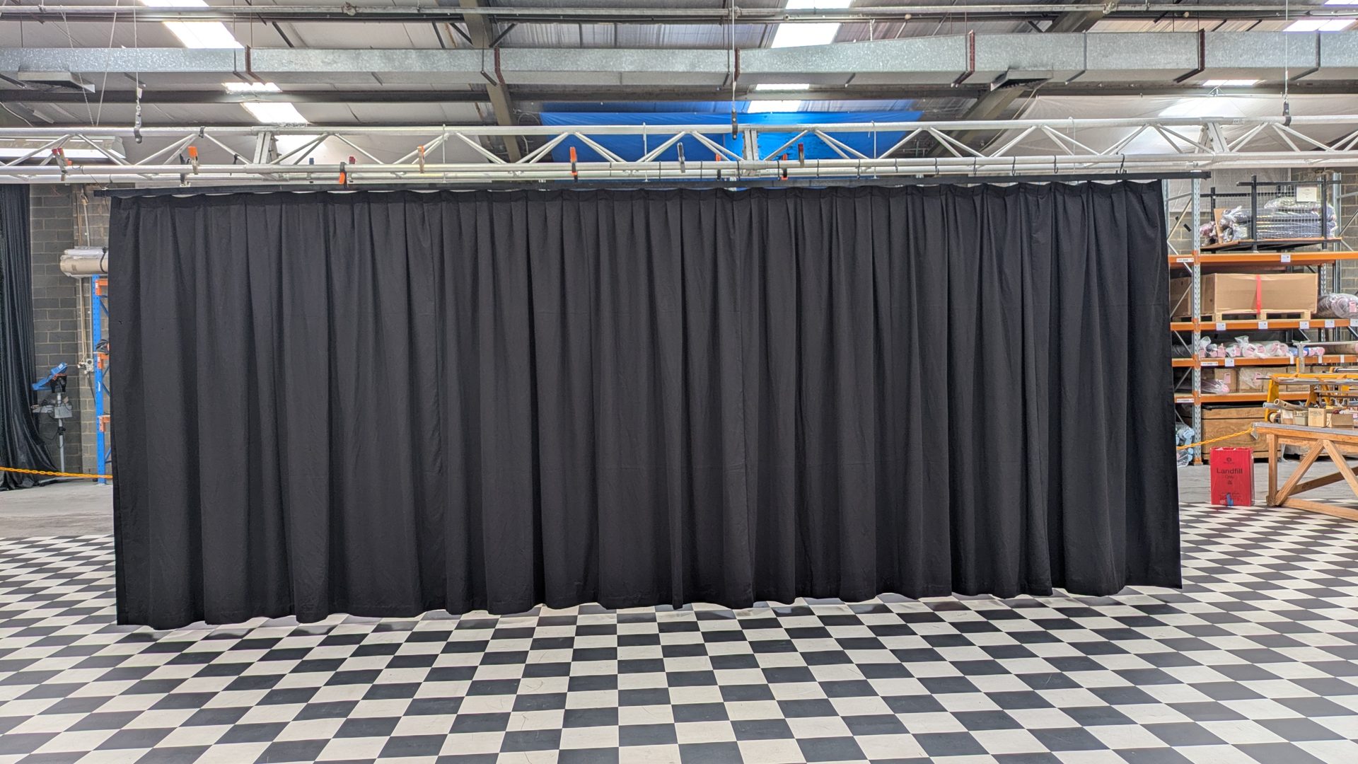 A finished black drape hung from truss in the workshop above a chequered floor