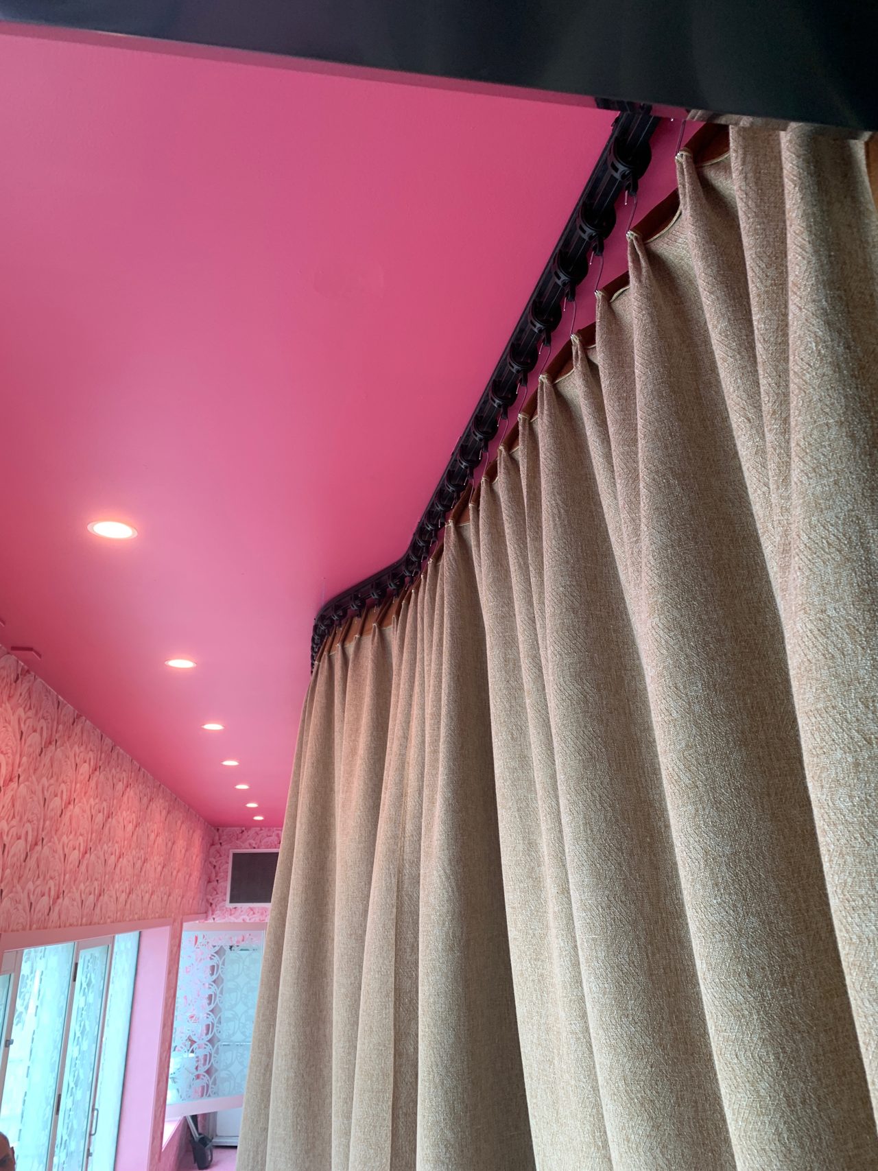 Linen drape with a wave heading on ceiling track under a pink ceiling