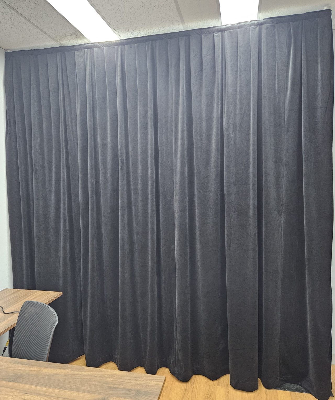 A dark velvet drape hung full height on the portable frame in an office