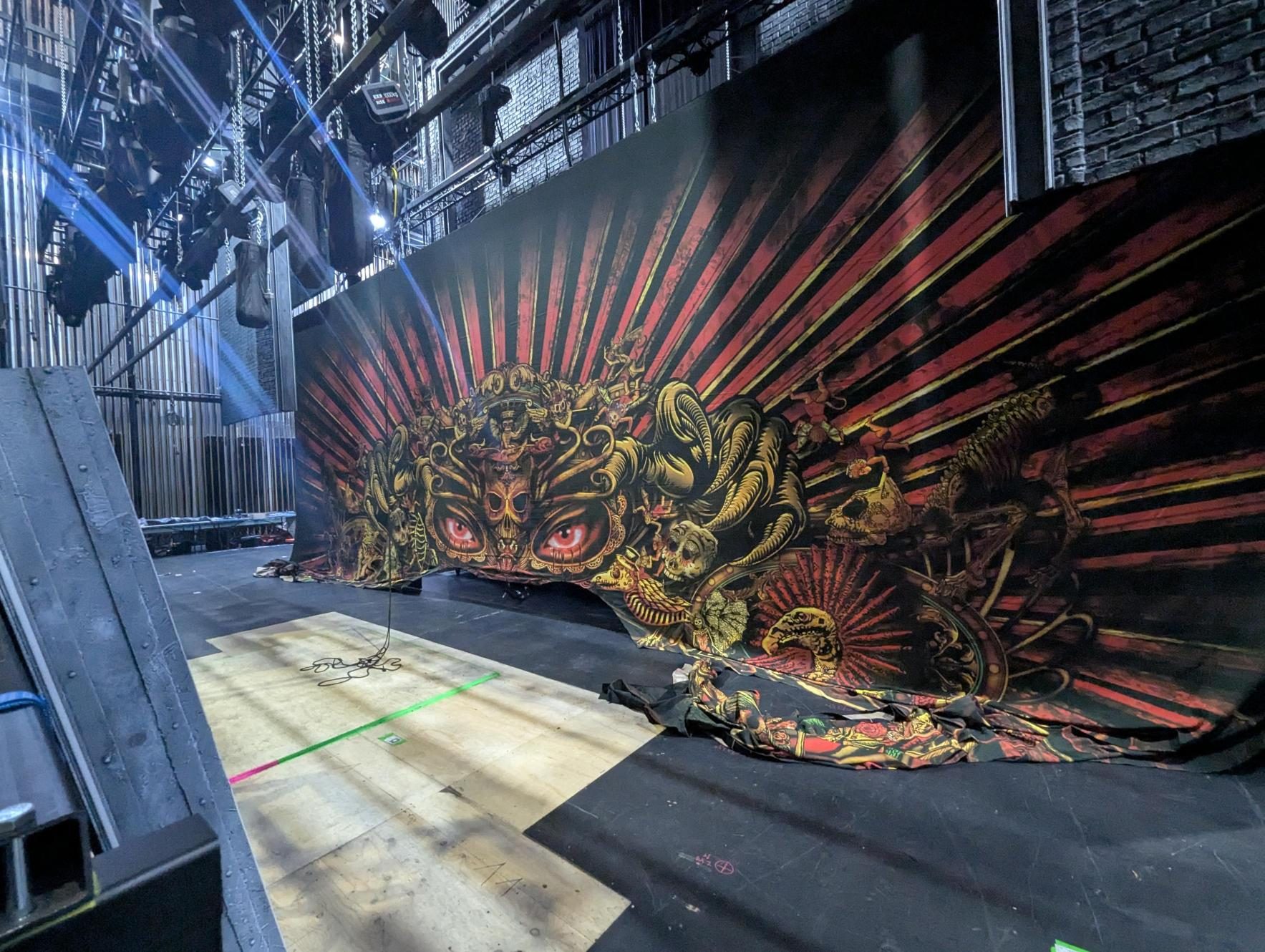 An ornate red and gold cloth hung upstage in a theatre, seen from the side of the stage
