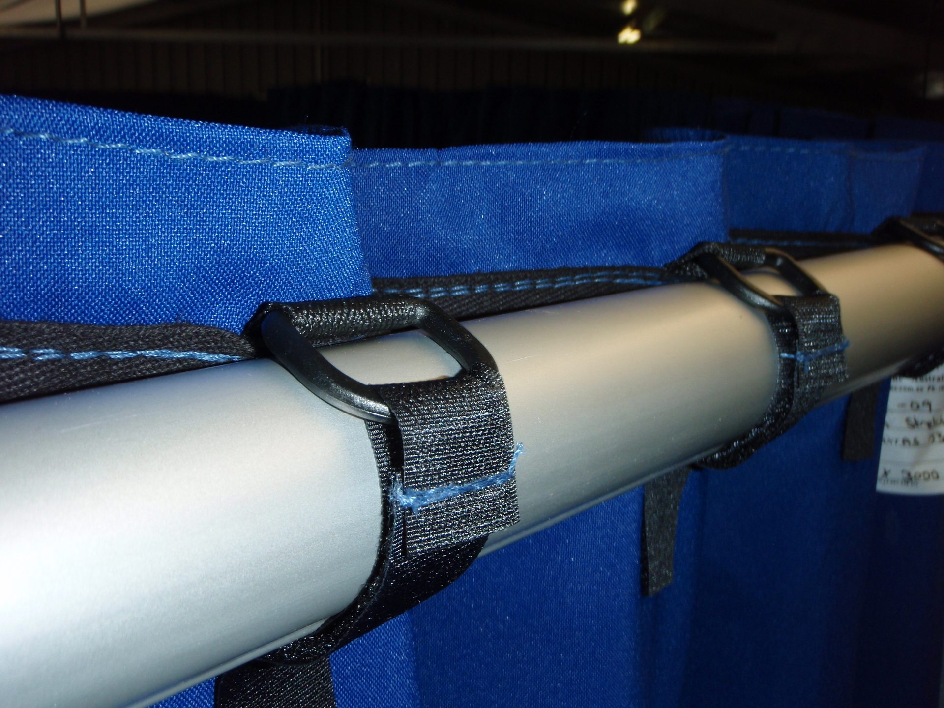 Close-up of the Option D header: a hook-and-loop tab fed through its D-ring, fastened flush around the crossbar