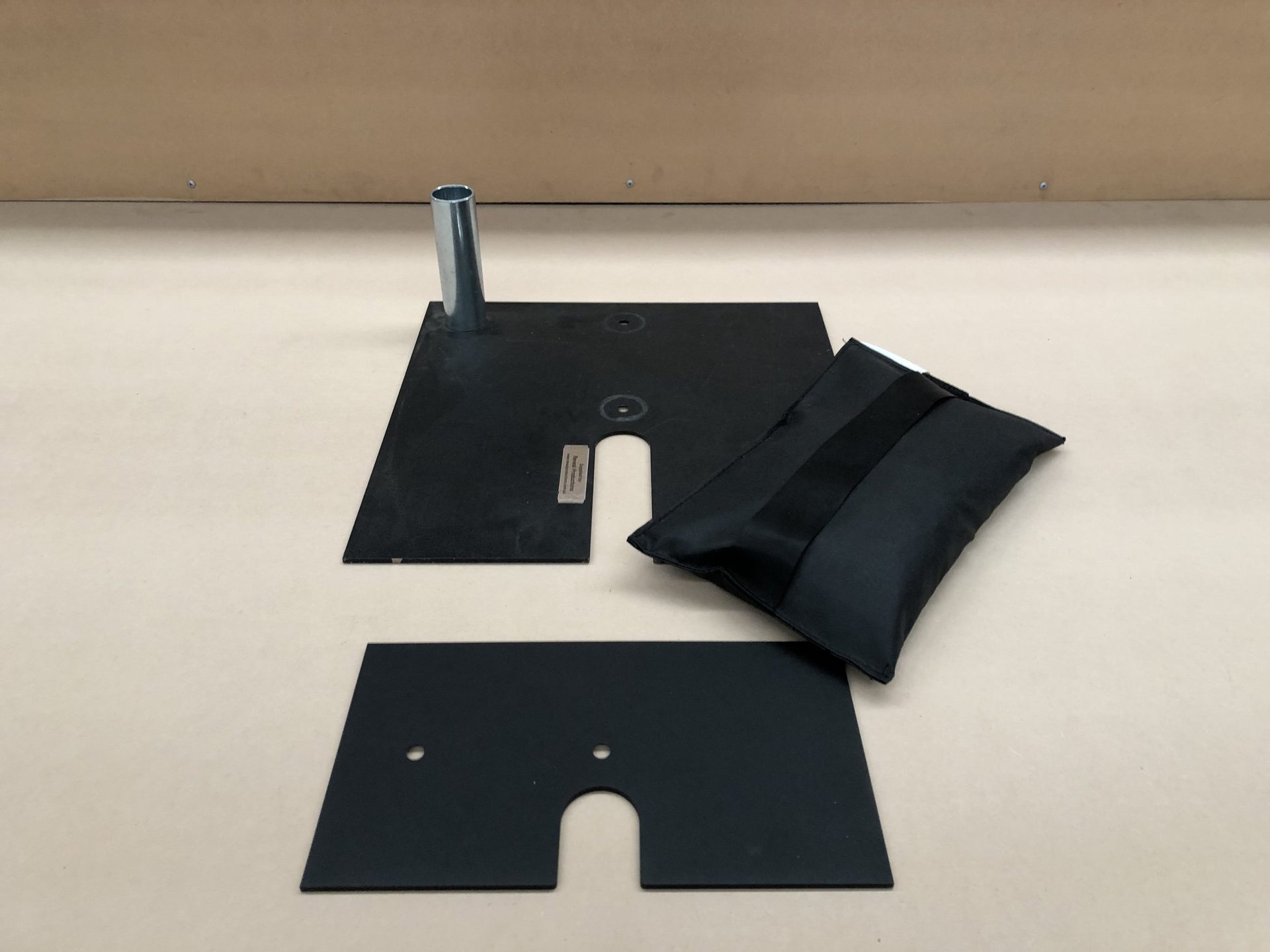 Two black base plates with a spigot and a shot bag on a pale floor