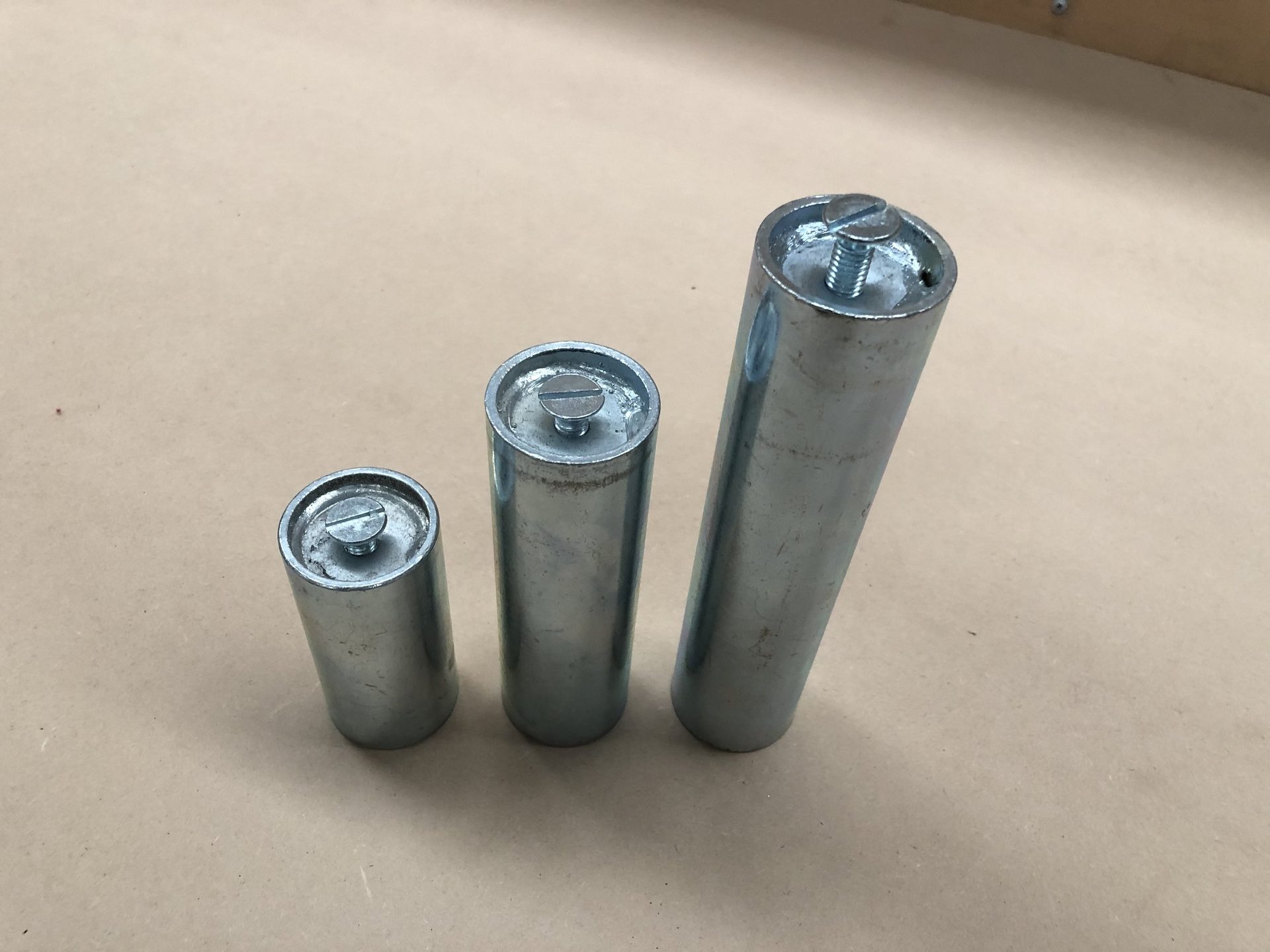 Three steel spigots of different sizes standing on a pale floor