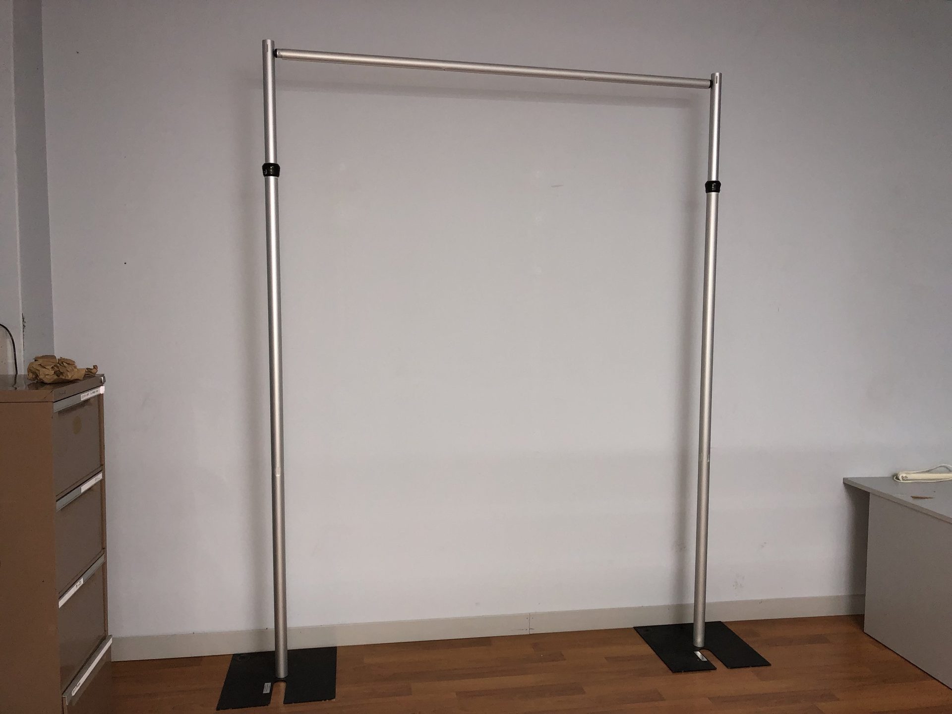 A bare portable drape bay: two telescopic uprights and a crossbar standing on base plates