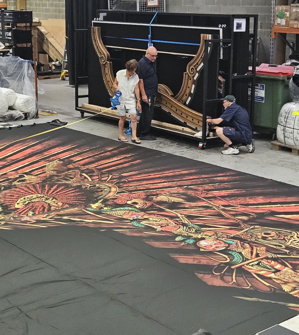 Reveal Productions team members assessing a printed scenic portal piece beside its frame in the workshop