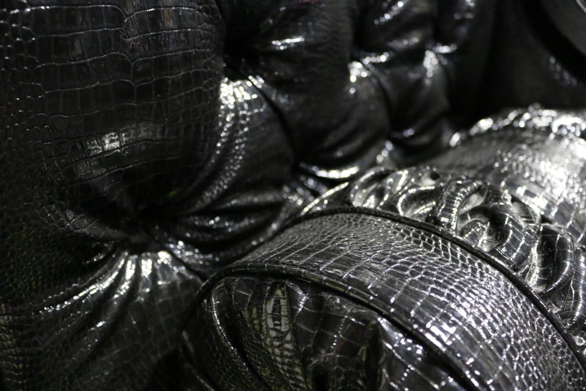 Close-up of glossy black faux-crocodile upholstery with detailed tufting from the stage furniture of Moulin Rouge! The Musical