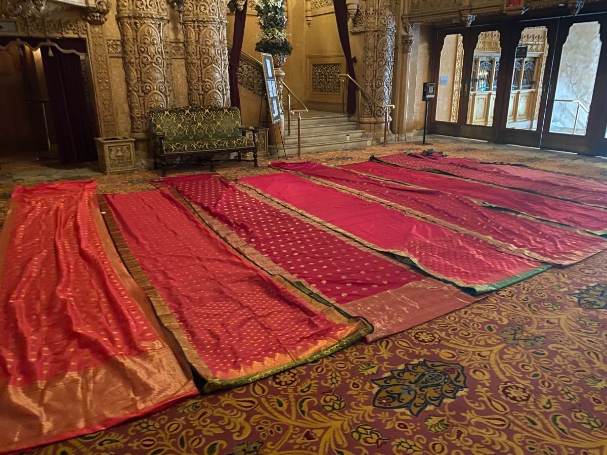 Rows of red and gold sari silks laid out across the carpeted foyer floor of the Regent Theatre