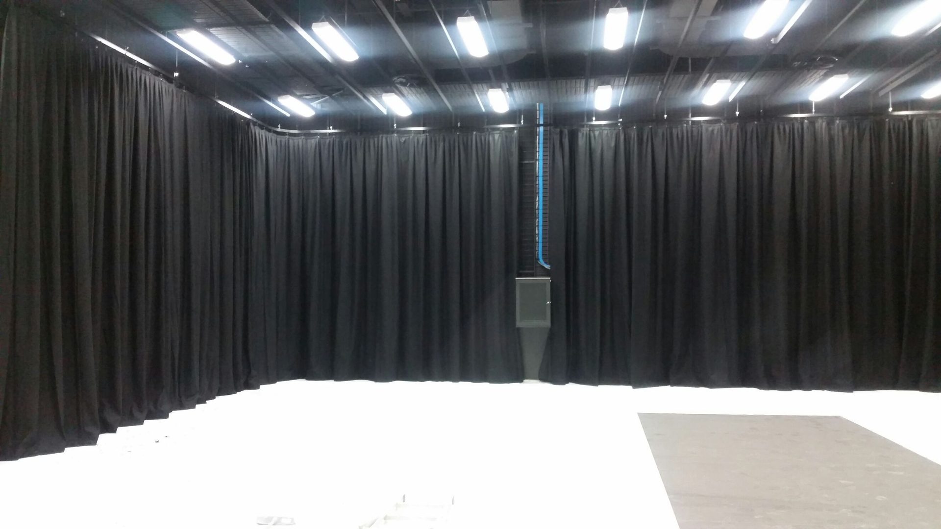 Black drapes on perimeter track around the white floor of a television studio