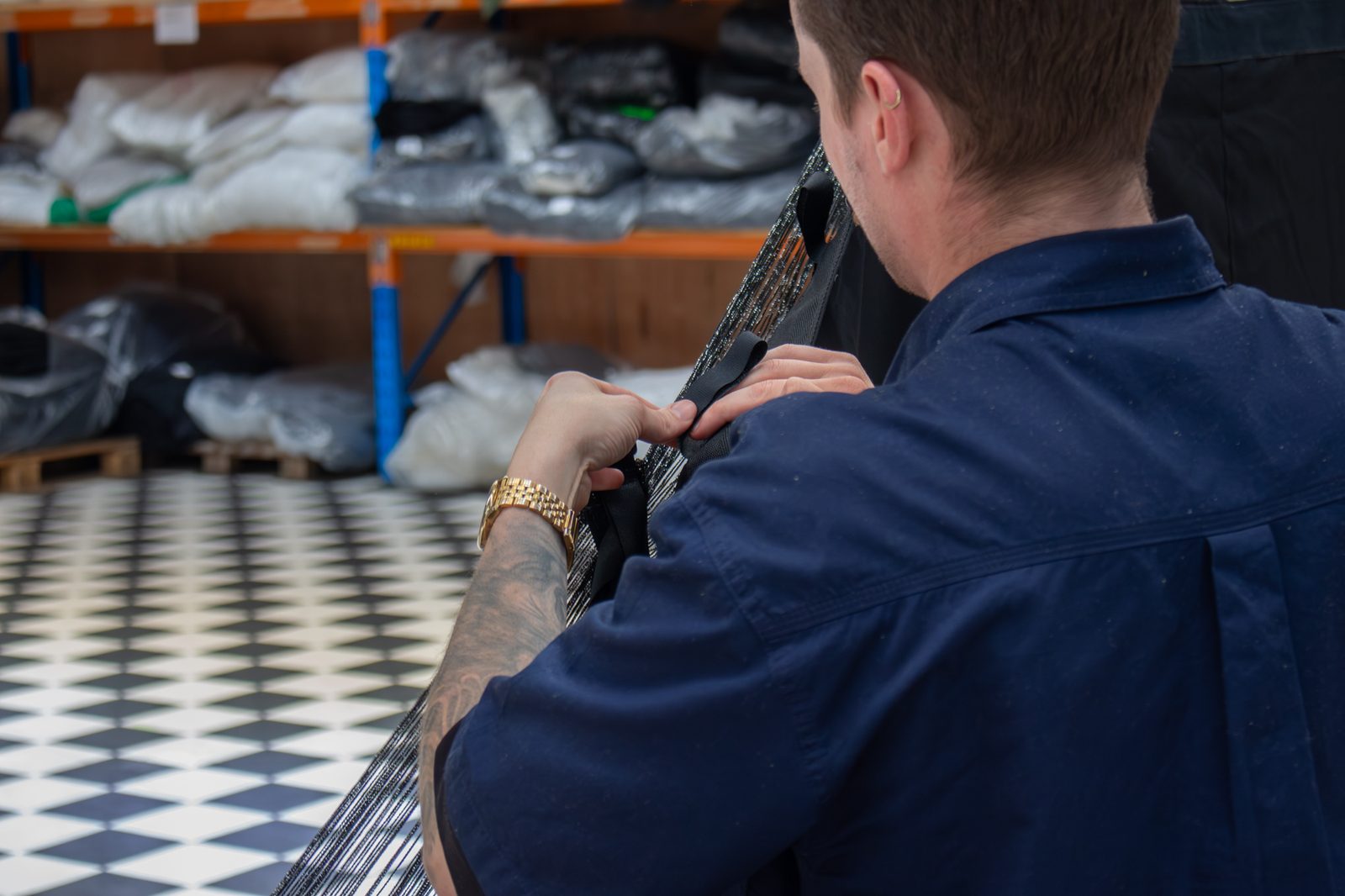 A staff member working a strap through the heading of a black drape in the workshop