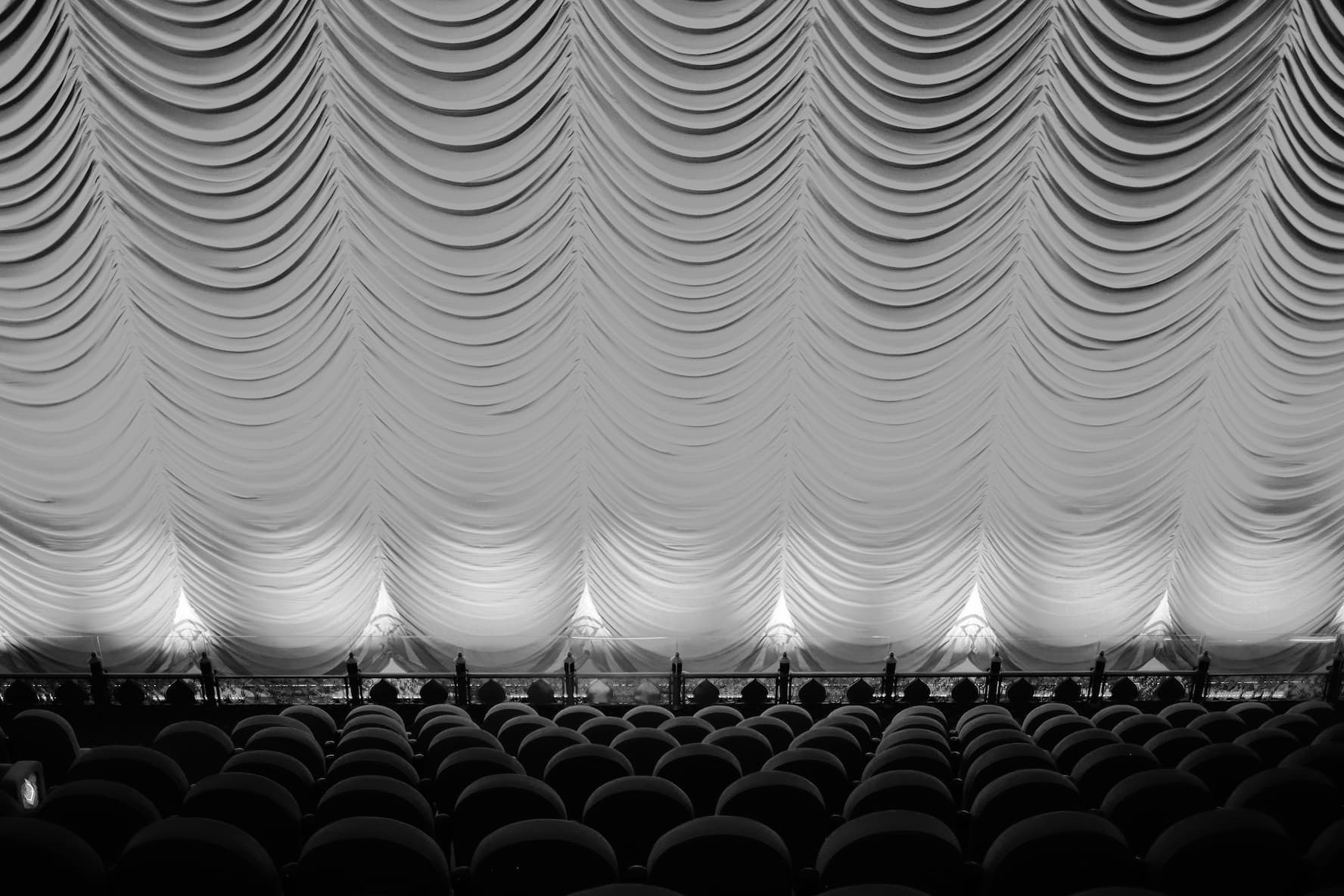 White austrian festoon curtain gathered into scalloped swags above rows of auditorium seating