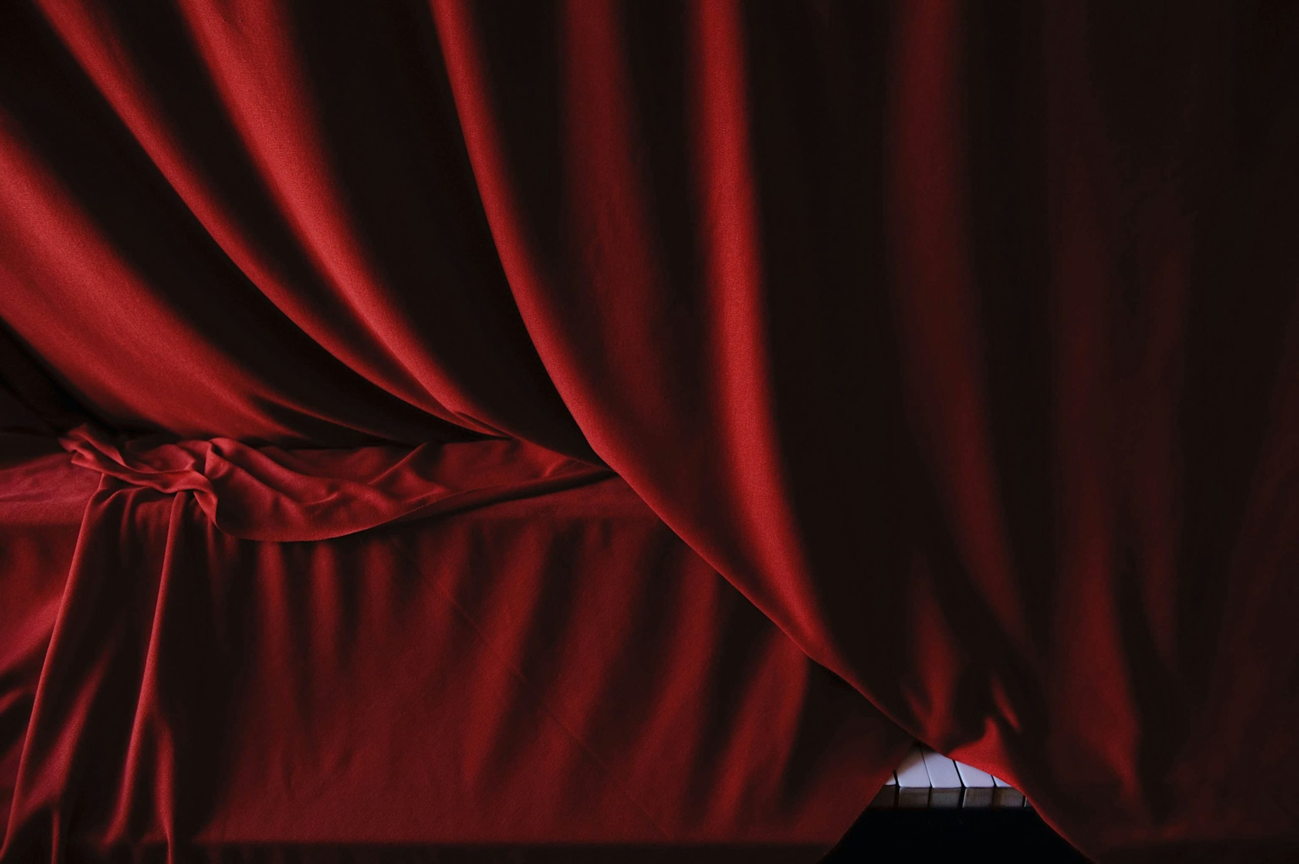 Deep red velvet house curtain catching stage light in full folds