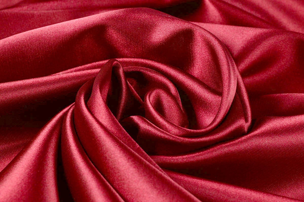 Red satin swirled to show its sheen, photographed in true colour