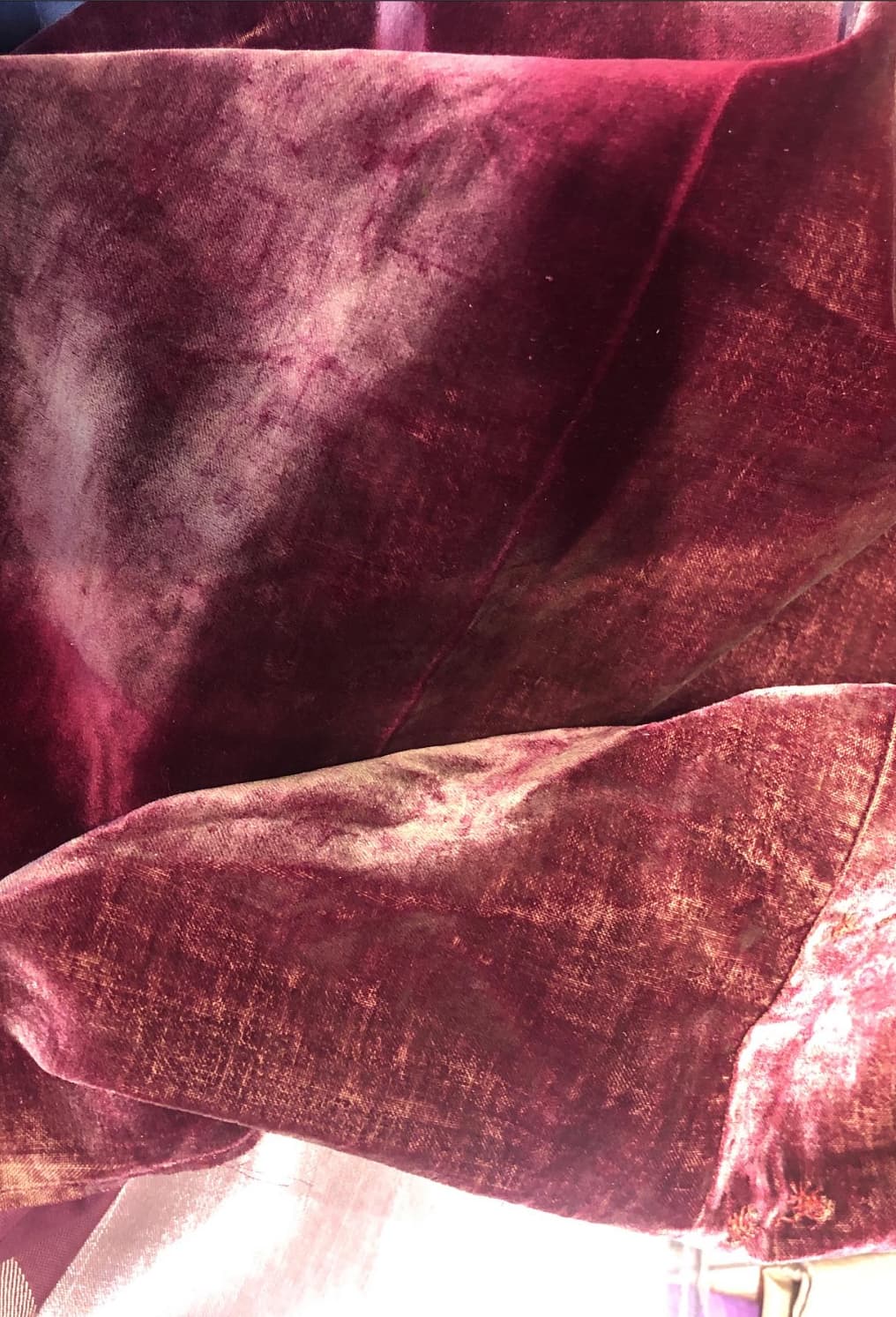 Deep red velvet with patches of faded, flattened pile