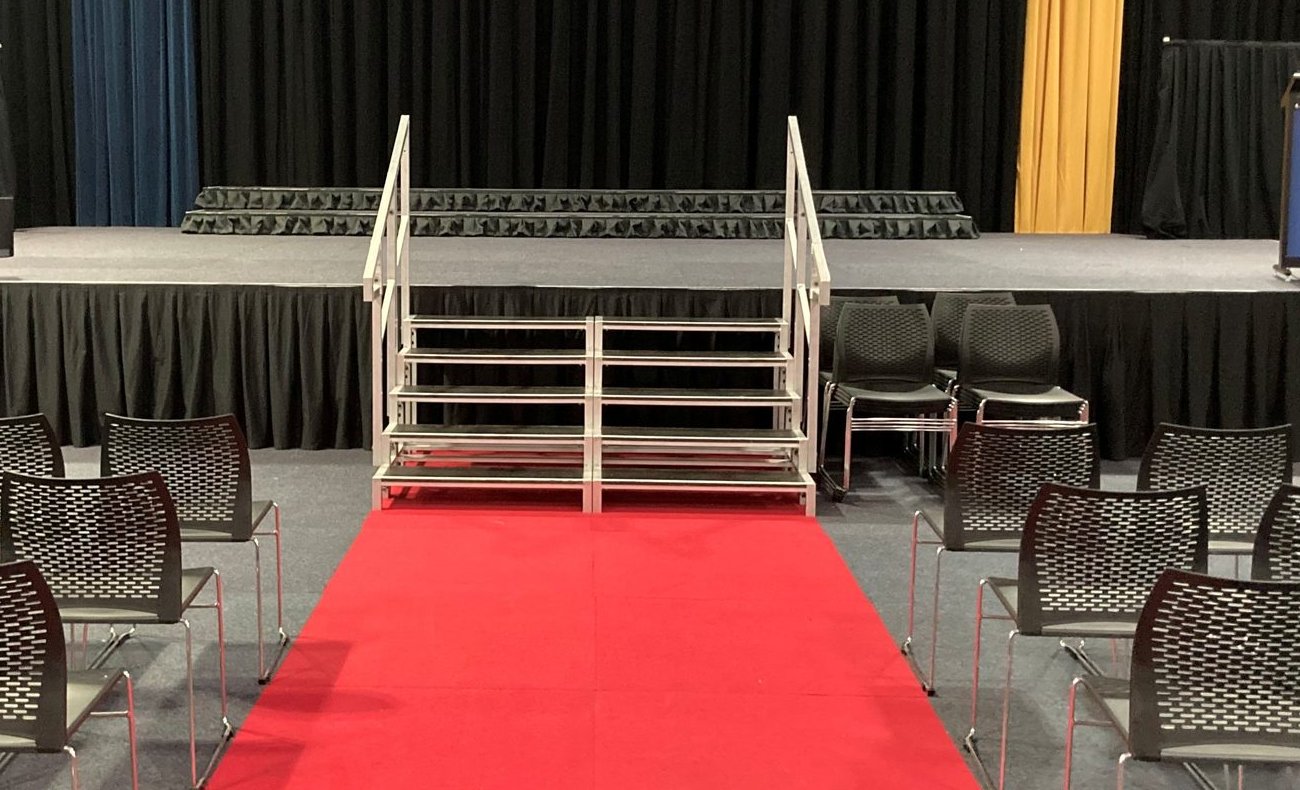 Pleated black skirting on a stage apron and ruffled skirting on the choir risers behind, with an aluminium stair unit front and centre